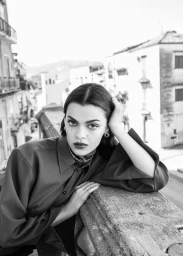 Black and white portrait of a woman resting her head on a stone balcony railing outdoors