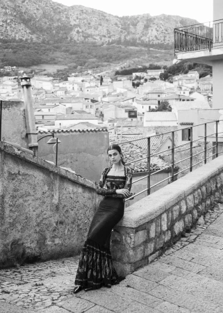 Model leaning against a stone wall in an Italian town street for 5ELEVEN Magazine fashion editorial.
