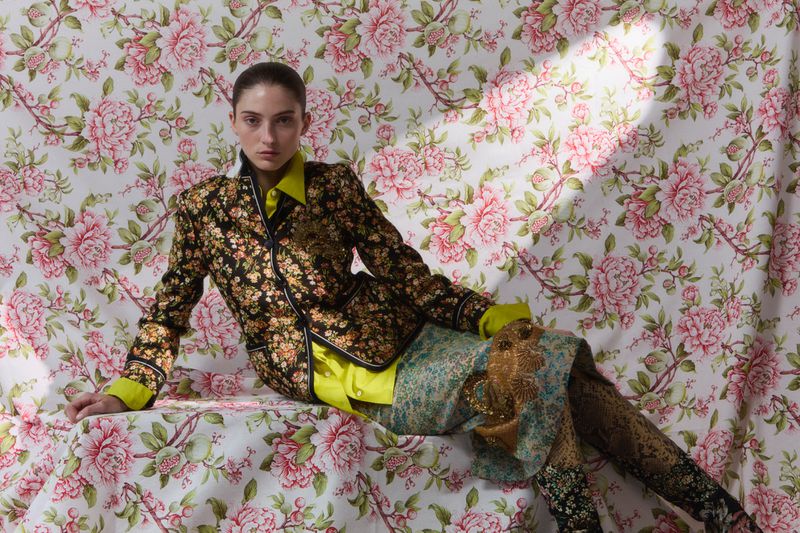 Model in floral blazer and patterned skirt posed against a matching pink floral backdrop for Flair Germany Florale Magie.