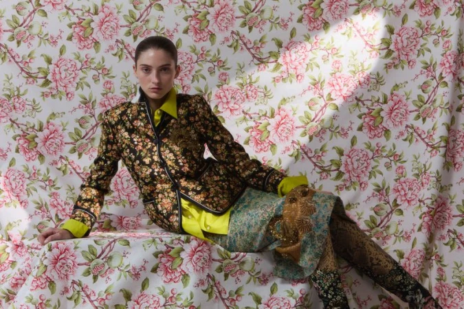 Model in floral blazer and patterned skirt posed against a matching pink floral backdrop for Flair Germany Florale Magie.