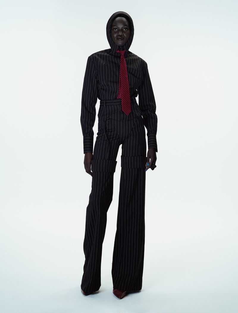 Model Caren Jepkemei wearing a pinstripe suit and matching hood with red tie for 10 Magazine editorial photographed by Ferry van der Nat.