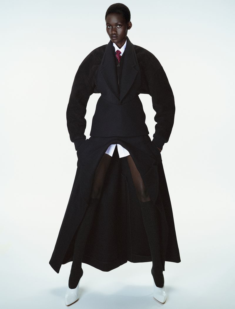 Model Caren Jepkemei wearing structural black outerwear and white heels against a white studio background for 10 Magazine