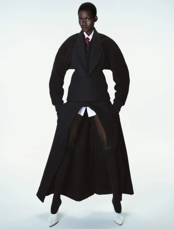 Model Caren Jepkemei wearing structural black outerwear and white heels against a white studio background for 10 Magazine