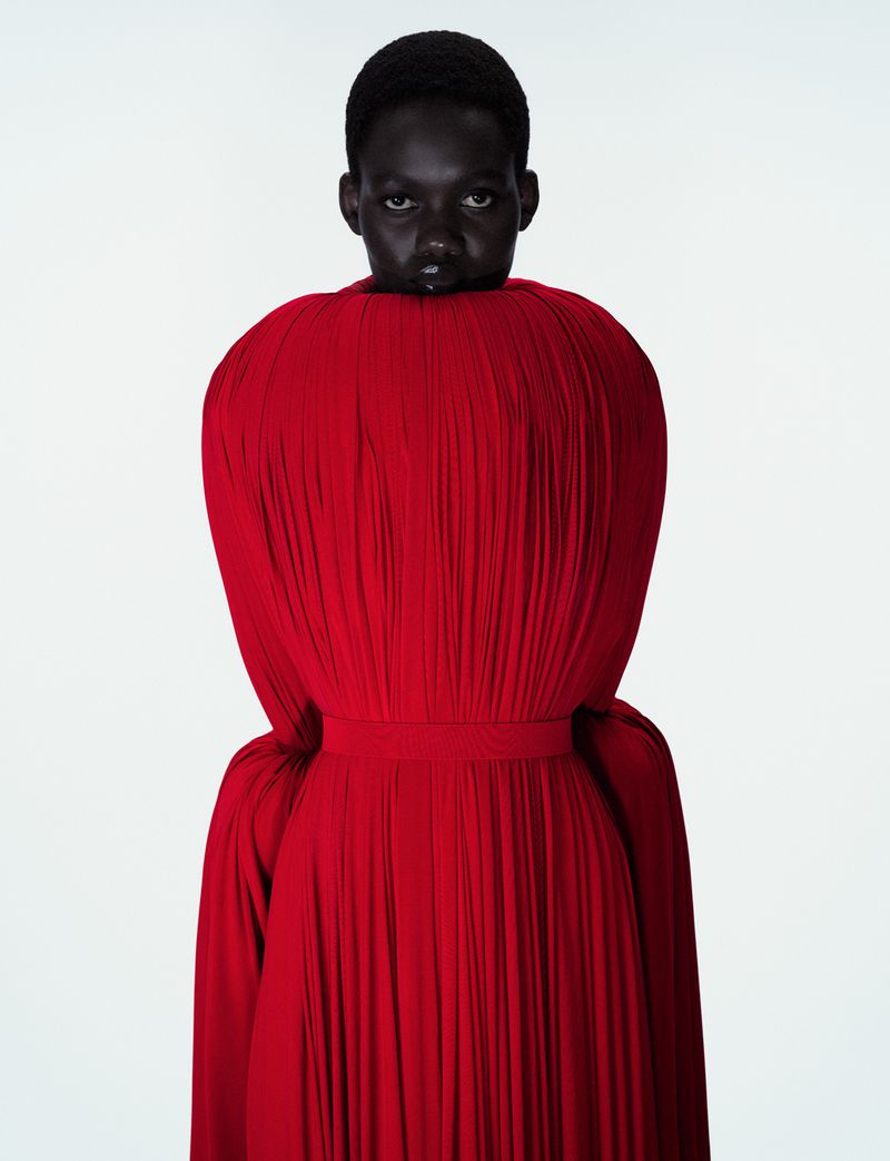 Model Caren Jepkemei in a voluminous red pleated dress against a plain white background for Jean Paul Gaultier Fantasia editorial