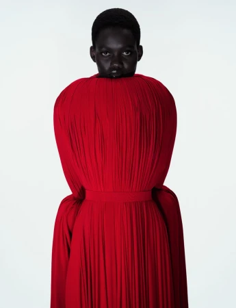 Model Caren Jepkemei in a voluminous red pleated dress against a plain white background for Jean Paul Gaultier Fantasia editorial