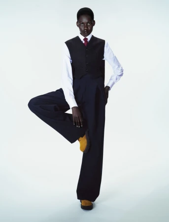 Model Caren Jepkemei balancing on one leg in a dark vest and trousers for a 10 Magazine editorial by Ferry van der Nat.