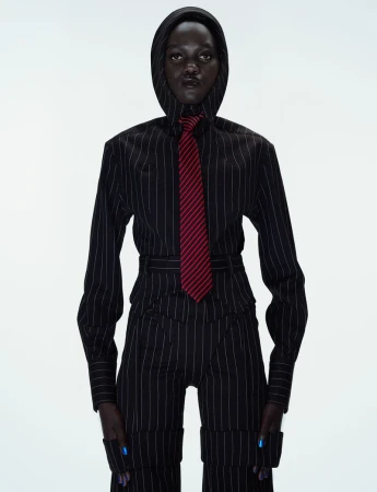 Model Caren Jepkemei in a pinstripe hooded top and matching trousers with a red tie against white background