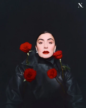 Woman in dark leather jacket surrounded by four red roses against a dark background for Noir Magazine editorial.