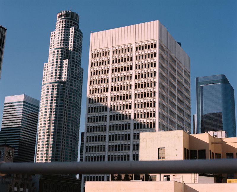 Low-angle view of several urban skyscrapers and modern office buildings against a clear blue sky