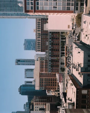 High-angle view of urban cityscape with diverse architectural buildings and parked vehicles under clear daytime sky