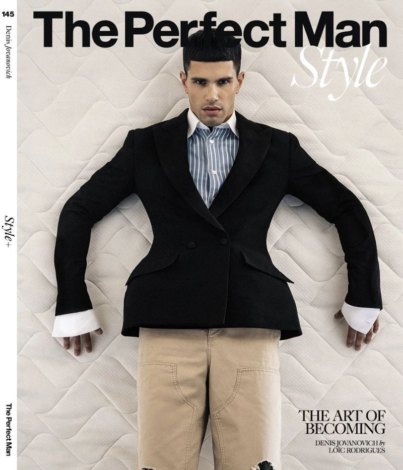 Editorial magazine cover featuring male model Denis Jovanovic wearing a black blazer and striped shirt lying on a quilted white mattress.