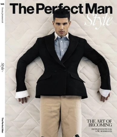 Editorial magazine cover featuring male model Denis Jovanovic wearing a black blazer and striped shirt lying on a quilted white mattress.