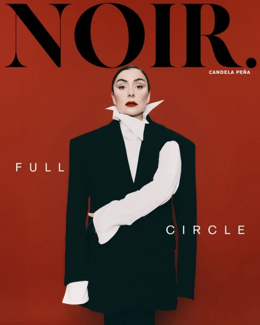 Woman in an oversized black blazer and white collared shirt against a bold red background for Noir Magazine June 2026 cover