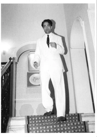 Robert Pattinson wearing a white suit and dark tie walking down a staircase for Dior, photographed by Luisa Pagani.