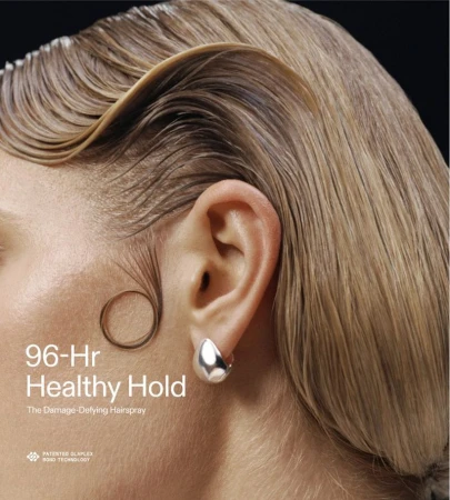 Close-up portrait of a woman with sculpted blonde hair, a circular baby hair curl on her cheek, and a silver earring.