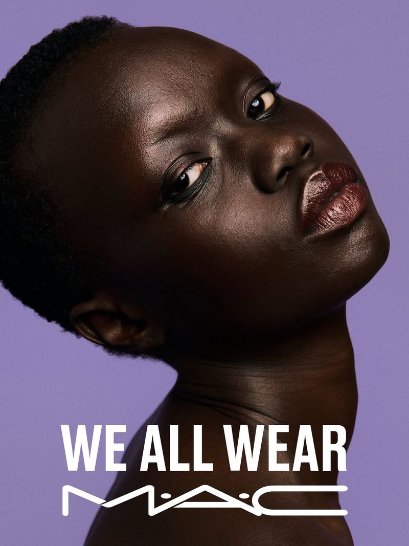 Close-up beauty portrait of a Black model with glossy dark lipstick against a solid purple backdrop for MAC Cosmetics
