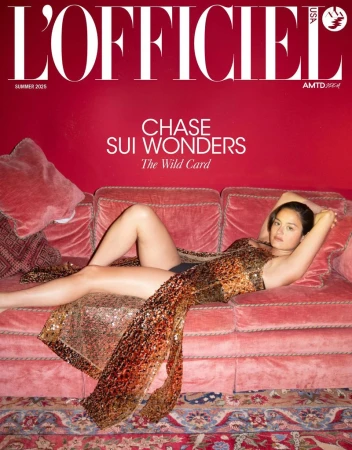 Magazine cover featuring Chase Sui Wonders in a shimmering dress, reclining on a plush pink sofa against a red backdrop, 'L'Officiel' title.