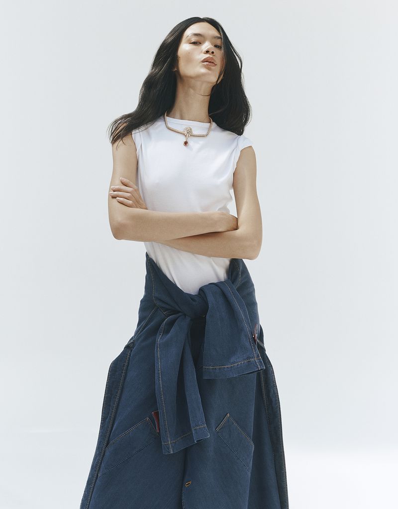 Model wearing a white t-shirt and denim skirt with arms crossed against a plain white background for Vogue China.