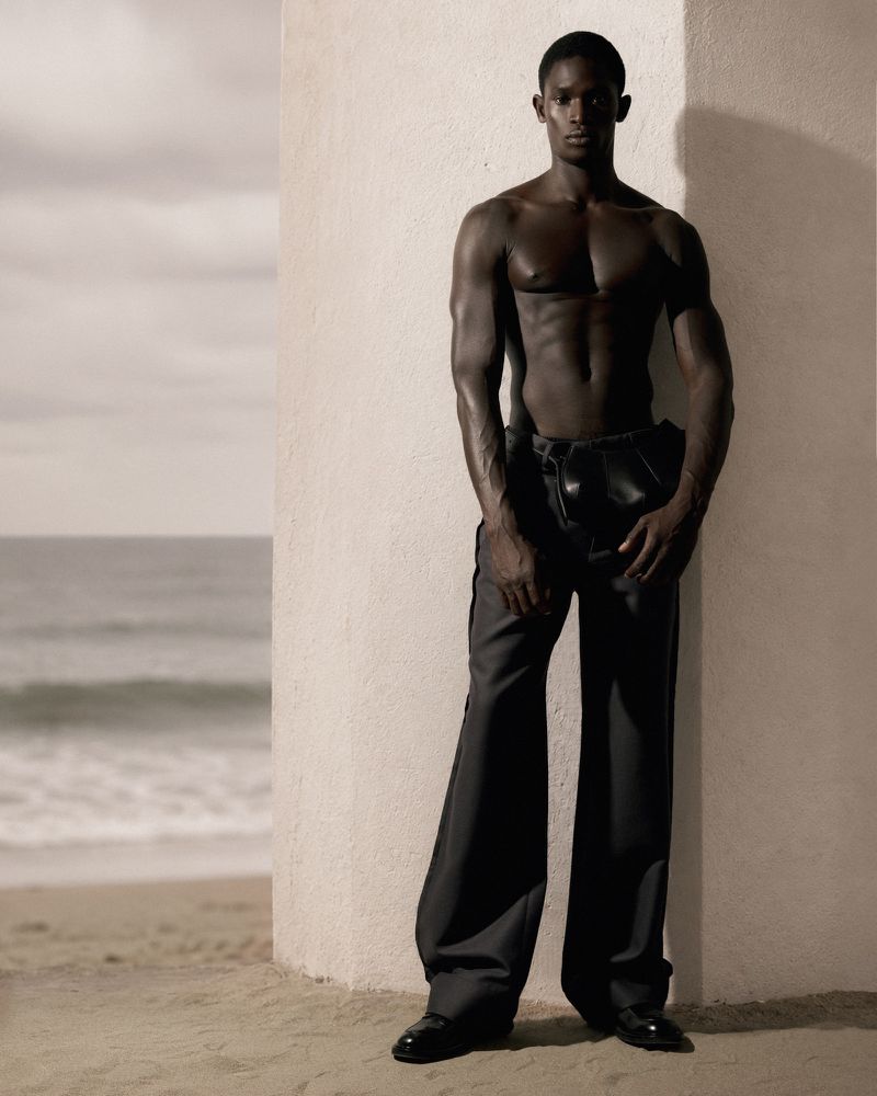 Shirtless black male model leaning against a concrete pillar by the ocean for GQ Turkey Behind the Sunset editorial