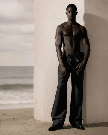 Shirtless black male model leaning against a concrete pillar by the ocean for GQ Turkey Behind the Sunset editorial