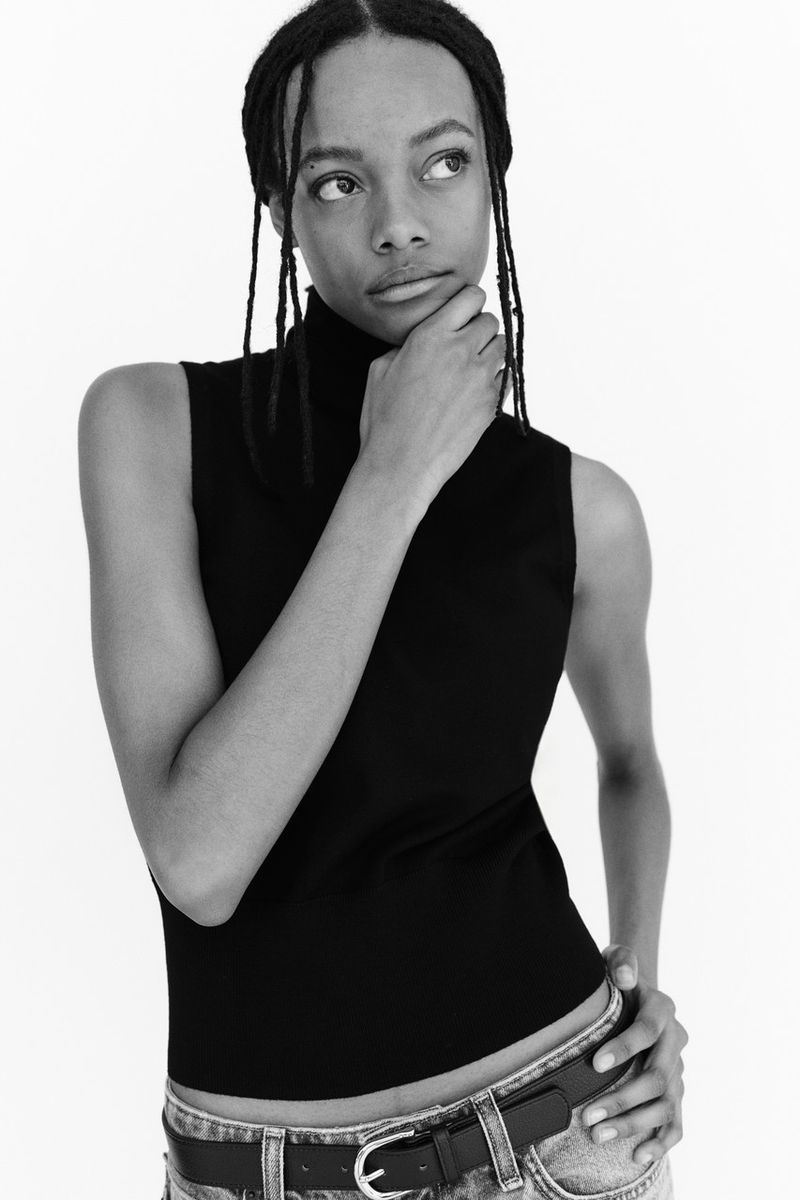 Model Nyela Hopster wearing a black sleeveless turtleneck for H&M Clean Lines project against a white studio background.