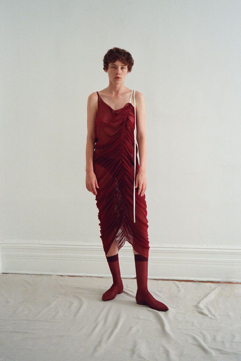 Model Annabelle Weatherly wearing a burgundy ruched dress and matching socks against a neutral background for Mel Usine S/S 27