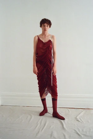 Model Annabelle Weatherly wearing a burgundy ruched dress and matching socks against a neutral background for Mel Usine S/S 27