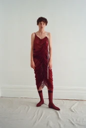 Model Annabelle Weatherly wearing a burgundy ruched dress and matching socks against a neutral background for Mel Usine S/S 27