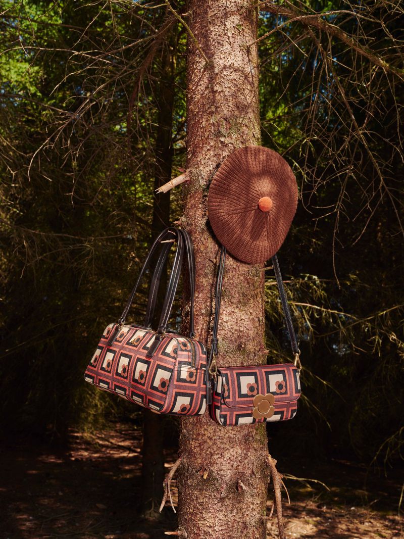 Orla Kiely AW26 fashion accessories hanging on a tree trunk in a forest setting