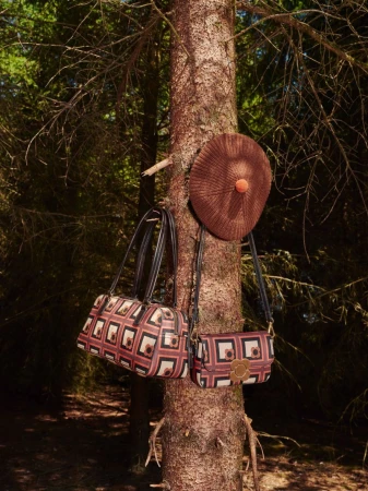 Orla Kiely AW26 fashion accessories hanging on a tree trunk in a forest setting