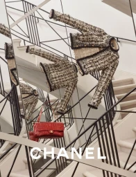 A tweed jacket and red handbag reflected in multifaceted geometric mirror panels on a staircase.