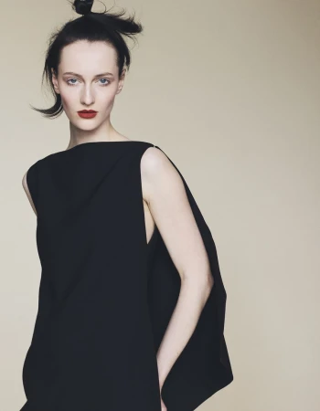 Model wearing a black sleeveless dress with bold red lipstick against a neutral backdrop for Harper's Bazaar Germany