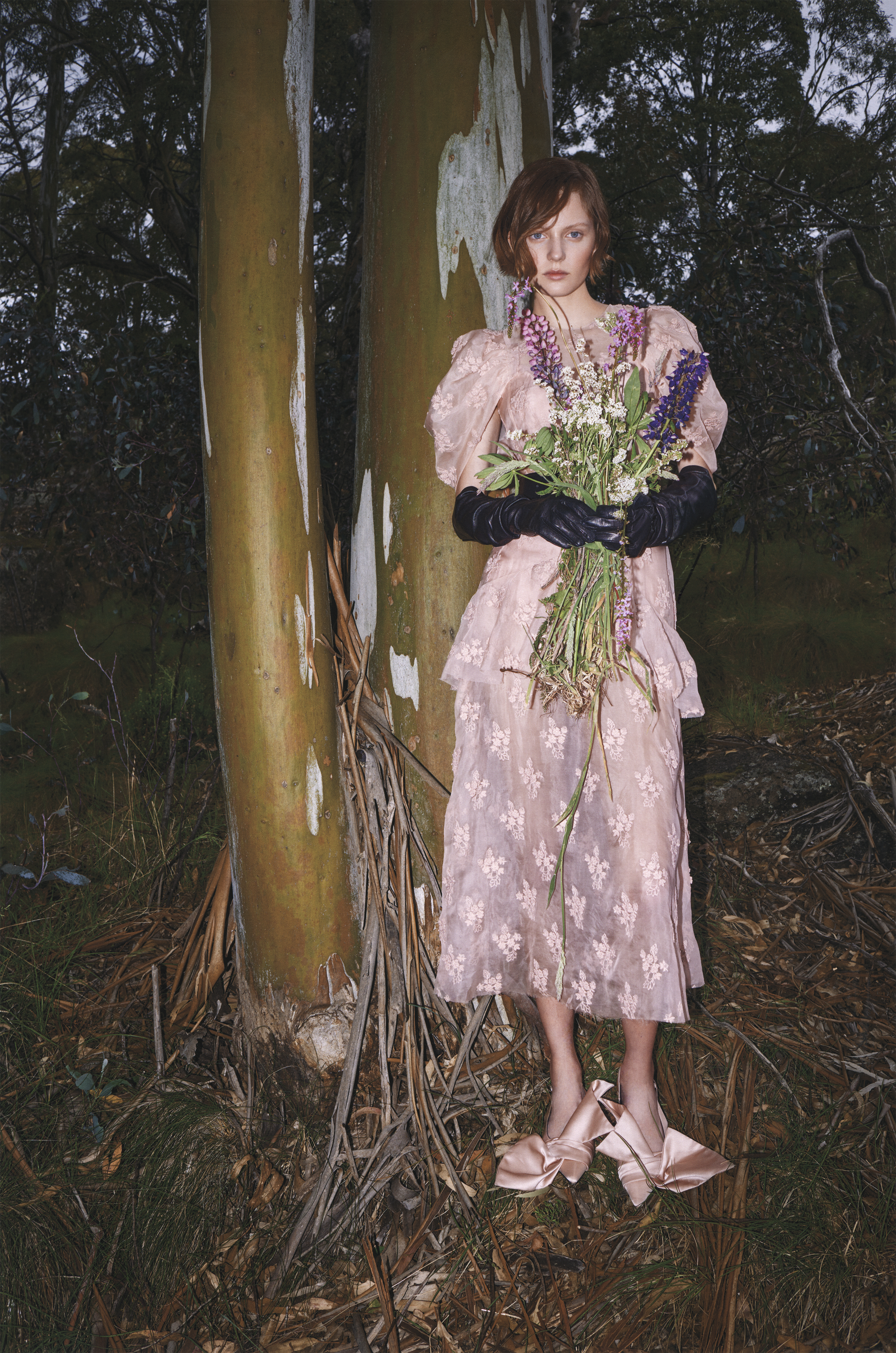 Model in pink dress and black gloves holding wildflower bouquet in forest by james giles for Vogue Polska High Country