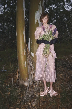 Model in pink dress and black gloves holding wildflower bouquet in forest by james giles for Vogue Polska High Country