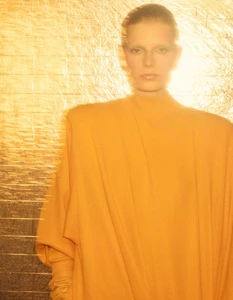 Model wearing a mustard yellow top against a textured golden foil background in a portrait for AnOther Magazine.