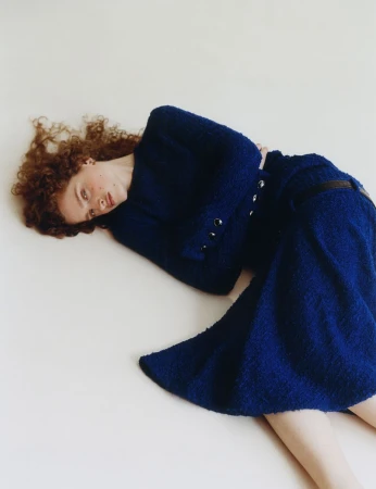 Model Aditsa Berzenia in a blue tweed dress lying down against a white background for 10 Magazine