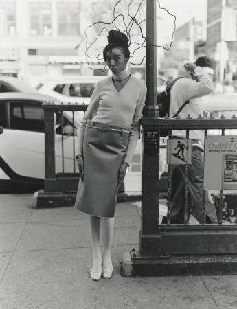 Model standing on a city sidewalk leaning against a subway entrance pole for 10 Magazine's Harlem Renaissance editorial