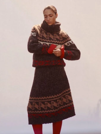 Model wearing a brown patterned turtleneck sweater and matching skirt against a neutral background