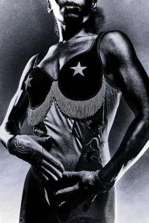 Black and white portrait of a muscular woman wearing a star-embellished bustier and gloves against a textured backdrop