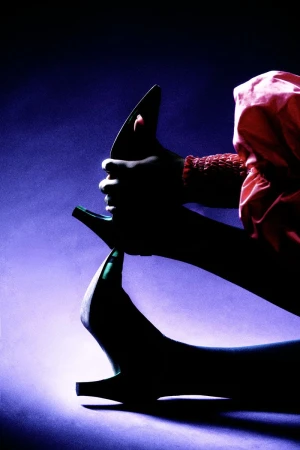 Close-up silhouette of a person wearing high-heeled shoes and pink fabric against a dramatic purple gradient background.