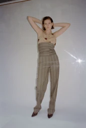 Model wearing striped halter top and matching high waist trousers posing against a white seamless background