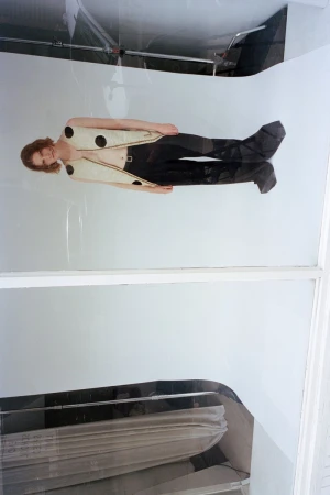 Model wearing a light-coloured patterned vest and dark trousers against a white backdrop