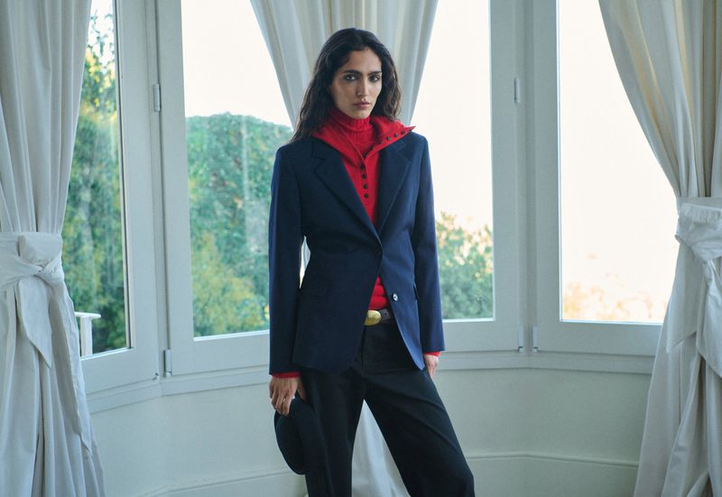 Model in dark blazer and red turtleneck standing before bright windows for Massimo Dutti