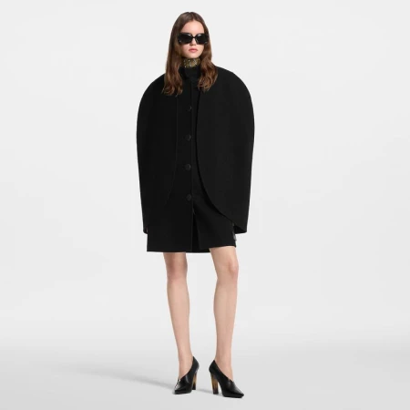 Model wearing a black coat and dark sunglasses against a seamless white background for Louis Vuitton fall winter 26