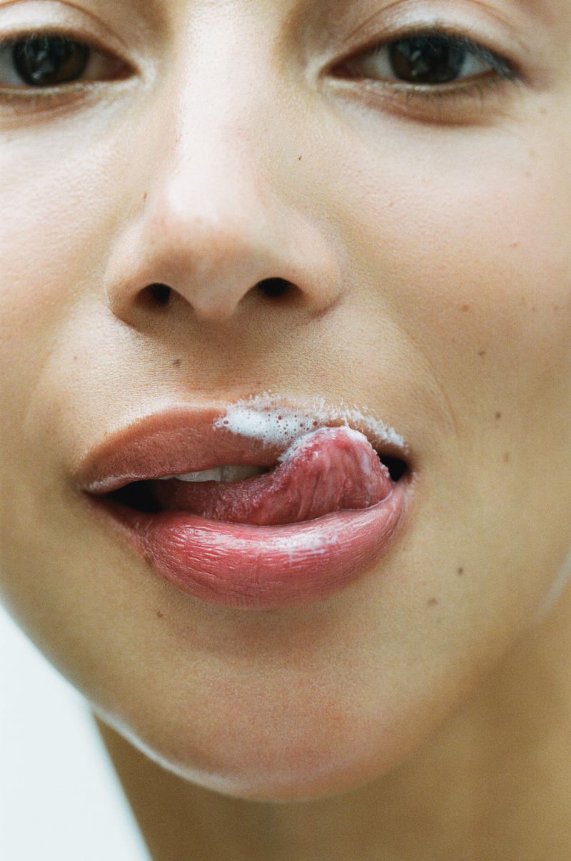 Close-up of a model licking lips with white cream on them for LORE Lil softie campaign by Estévez and Belloso