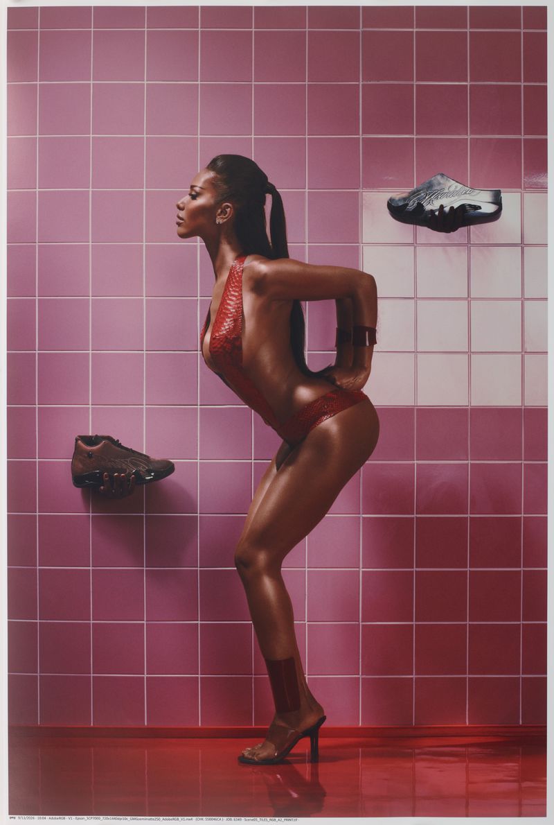 Model in red swimsuit posing against pink tiled wall with floating shoes in Mowalola x Jordan campaign