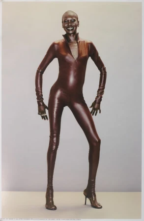 Model wearing a glossy dark brown leather catsuit against a seamless grey backdrop for Mowalola