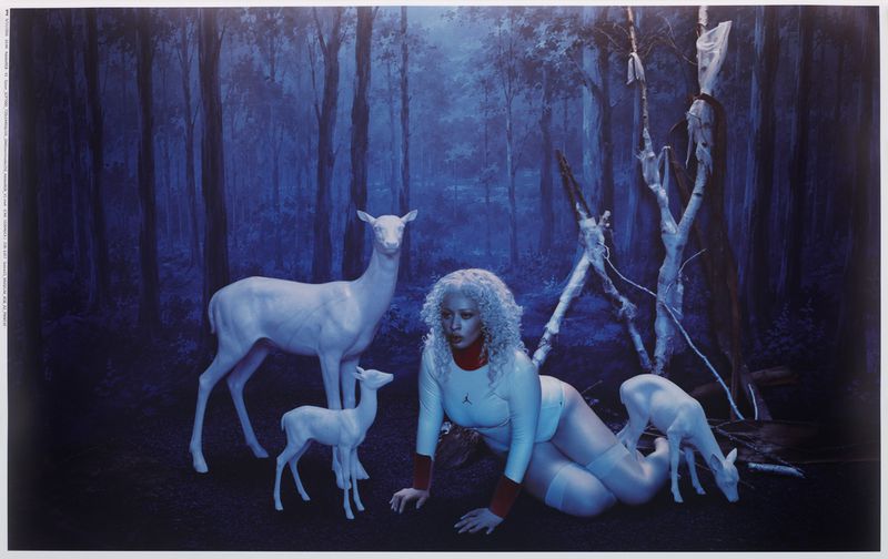 A blonde model kneeling in a dark forest surrounded by white deer statues for Mowalola x Jordan.