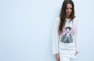 Model Libby Taverner wearing a white t-shirt and pink crop top against a light grey seamless studio backdrop.