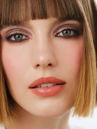 Close-up portrait of a woman with short brown bob hair, blue eyes, and peach lips for Mojeh Magazine